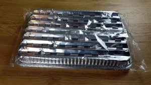 Die BBQ Alu-Grillpfanne auf den Kopf gelegt mit 10 Stück aufeinander gestapelt, leicht schräg von oben fotografiert