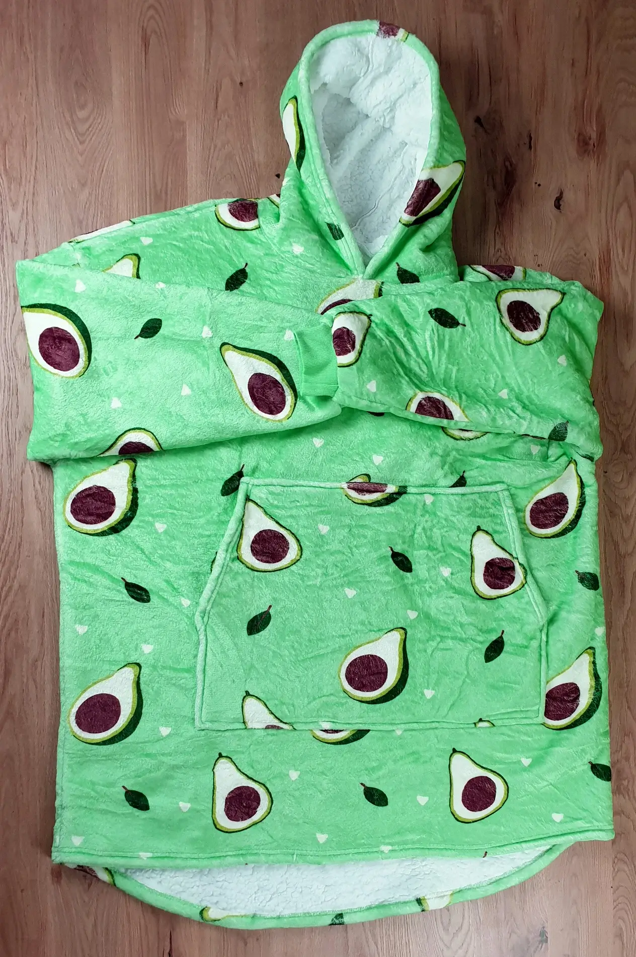 Ein Photo des Decken-Hoodies im Avocado-Design auf den Tisch gelegt mit der Vorderseite zur Kamera