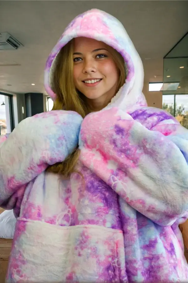 Eine junge Frau präsentiert den Decken-Hoodie mit dem Universums-Design