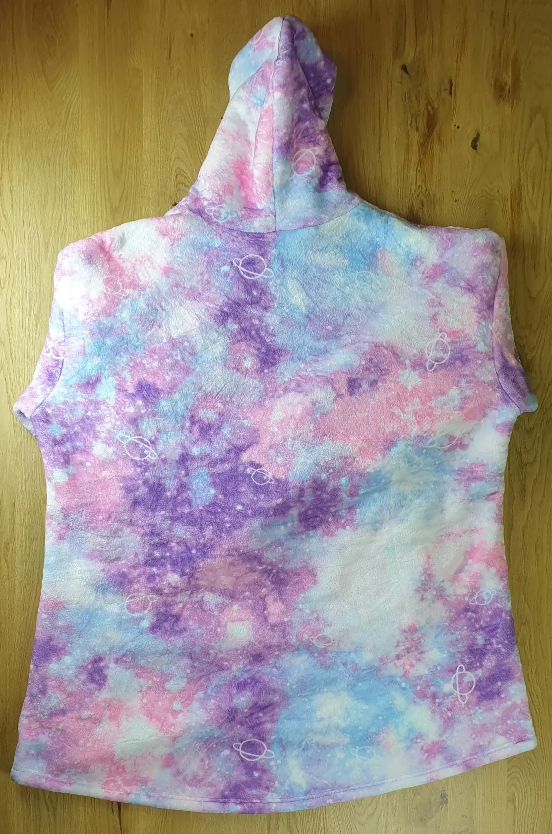 Ein Photo des Decken-Hoodies im Universum-Design auf den Tisch gelegt mit der Rückenseite zur Kamera