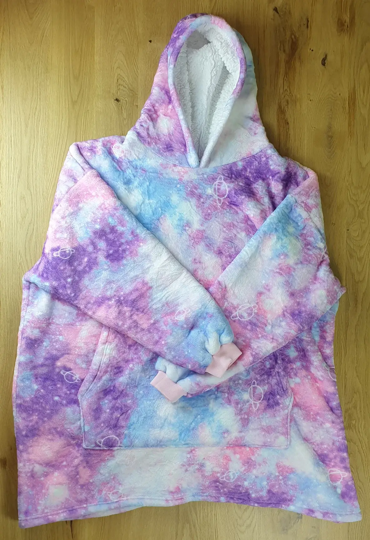 Ein Photo des Decken-Hoodies im Universum-Design auf den Tisch gelegt mit der Vorderseite zur Kamera