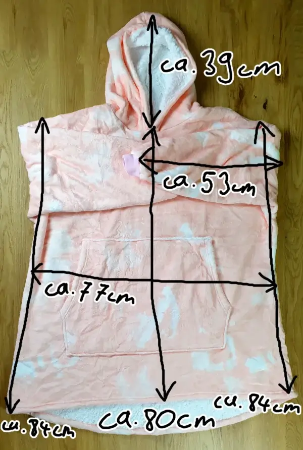 Ein Bild vom Decken-Hoodie im Pinke-Wolke-Design auf dem Tischh liegend mit den Maßen des Decken-Hoodies eingezeichnet