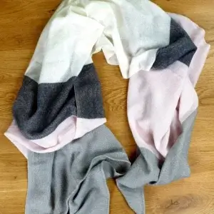 Ein großer flauschiger Schal mit rosa, schwarz, weißen und grauen Streifen.