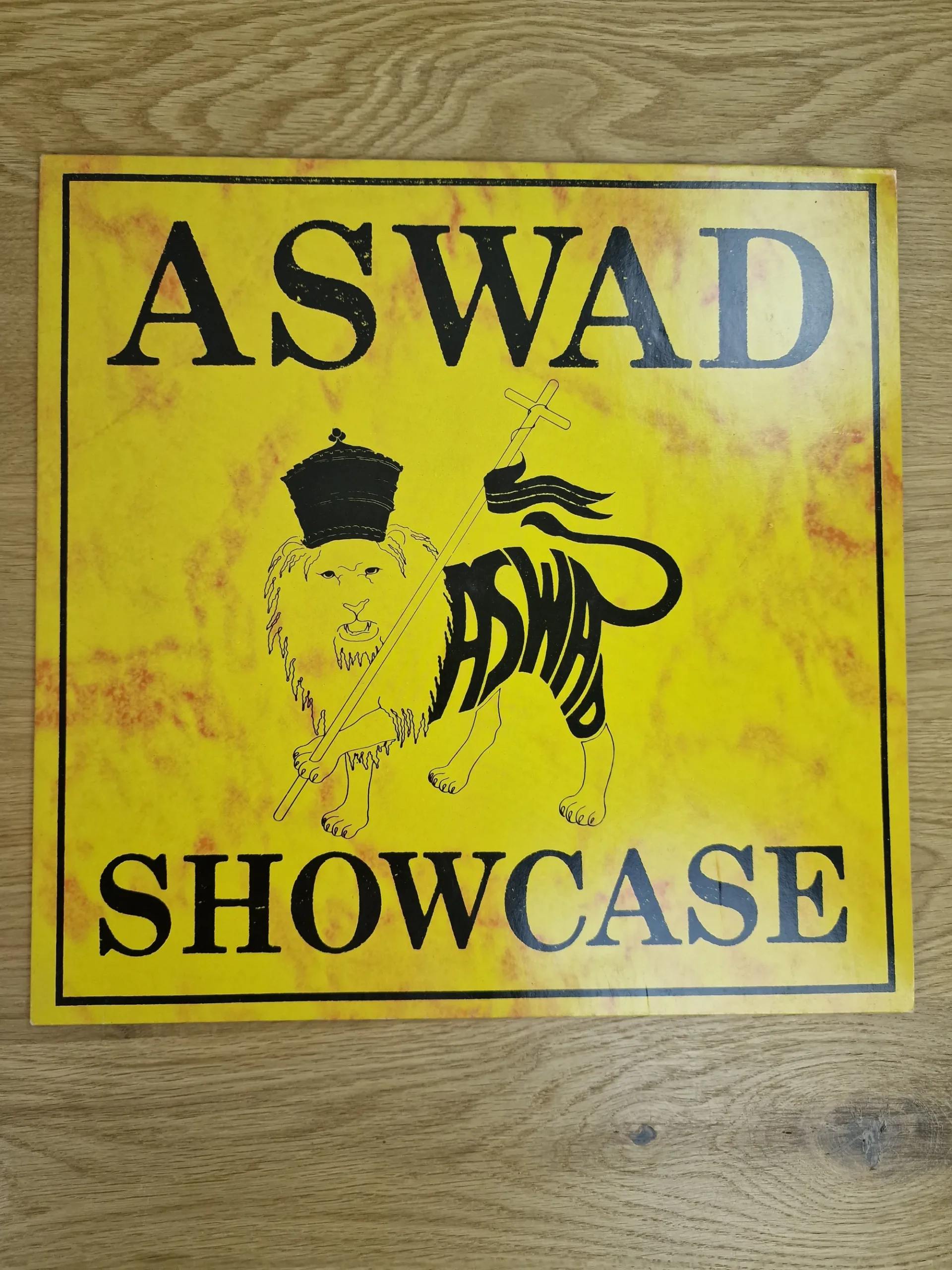 Vorderseite des Reggae-Albums Aswad Showcase mit gelbem Cover und Lion-of-Judah-Motiv