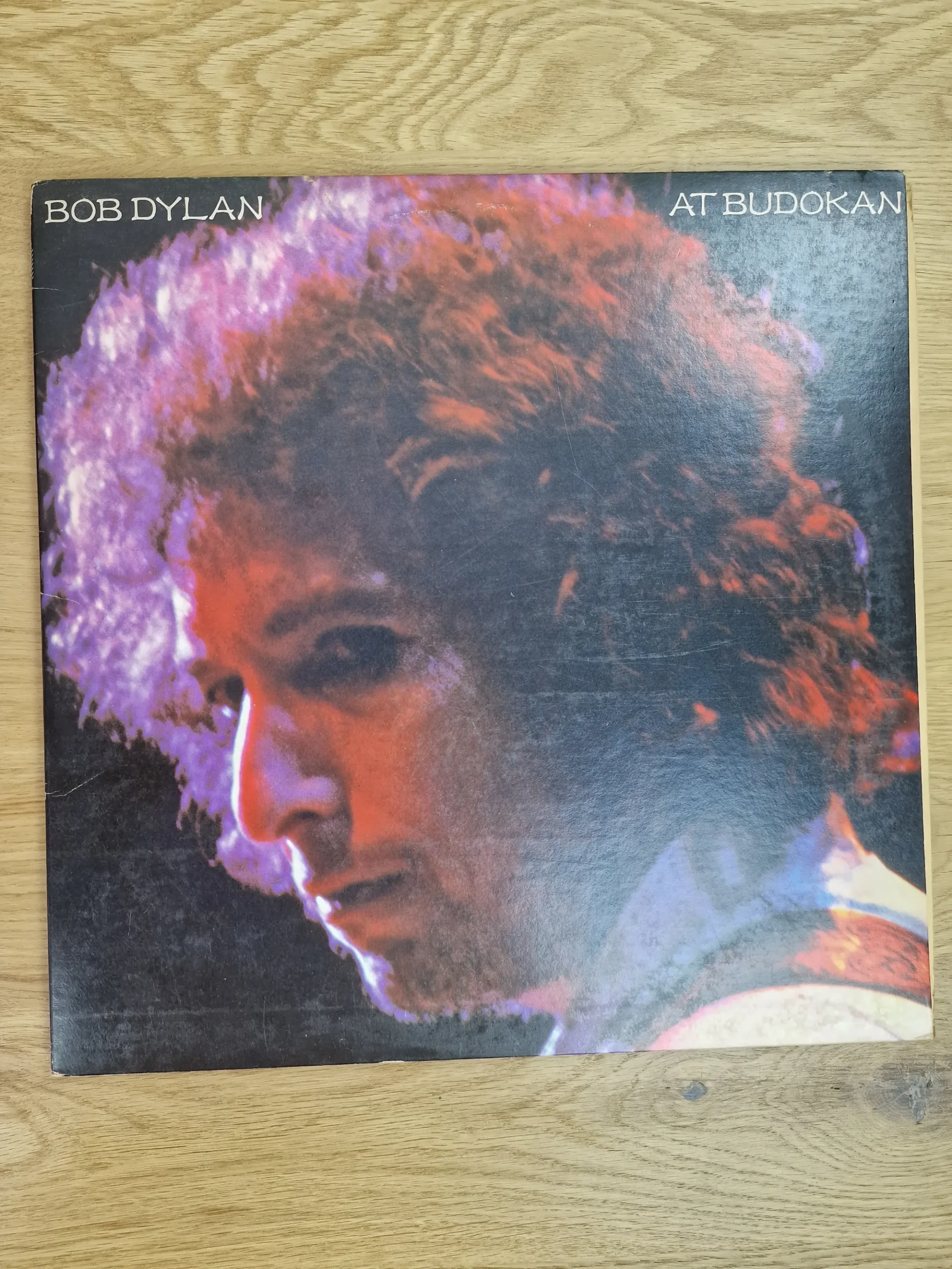 Frontcover der Schallplatte Bob Dylan At Budokan mit farbigem Porträt von Bob Dylan