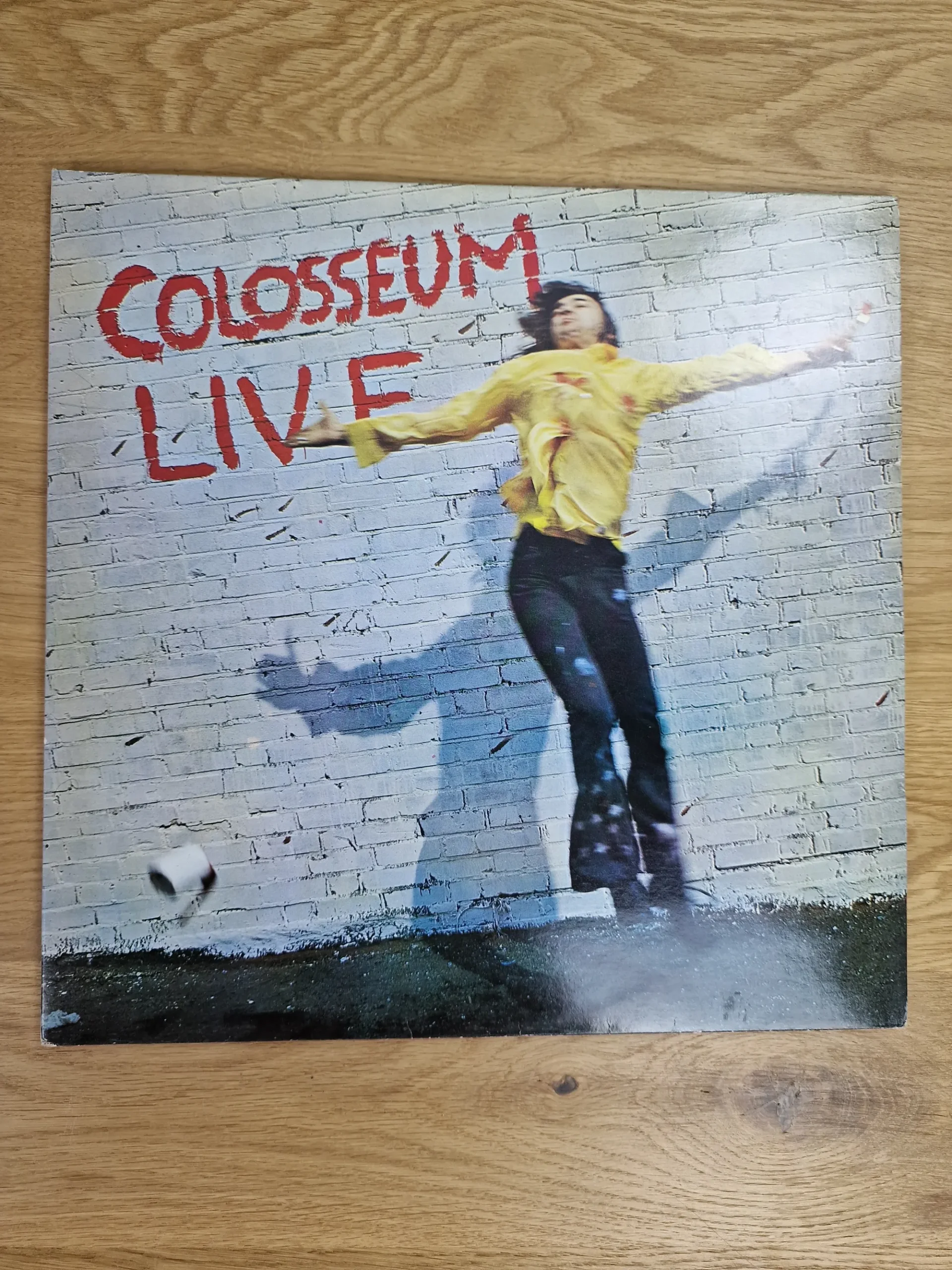 Vorderseite des Album-Covers Colosseum Live mit Graffiti-Schriftzug auf einer Ziegelwand